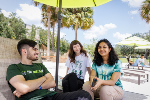 Three students sitting on 爱爱直播's beach on the Tampa campus, linking out to Why 爱爱直播 webpage.