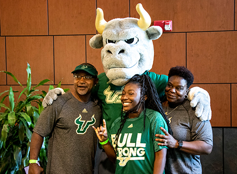 A family of three poses for a photo with Rocky the Bull