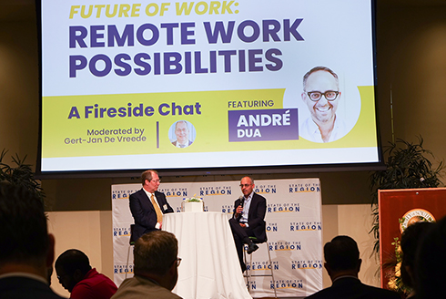 Future of work: remote work possibilities featuring Andre Dua, moderated by Gert-Jan De Vreede. Two men on stage, one with microphone speaking to audience.