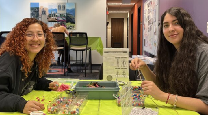 Two female ֱ international students take a break from classes to make friendship bracelets in the International Student Success Center during "De-Stress Fest"