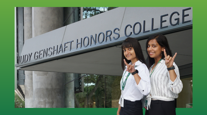 two Indian females dressed in black pants and white shirts stand outside the front of the Honors College building at ֱ